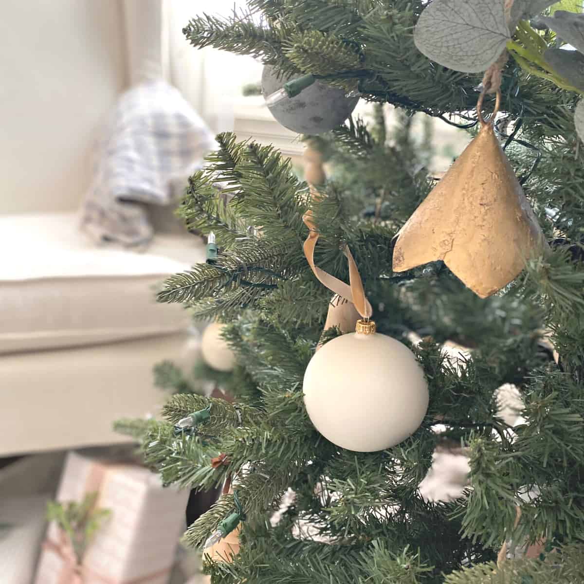 White and brass Christmas ornaments adorn a Christmas tree