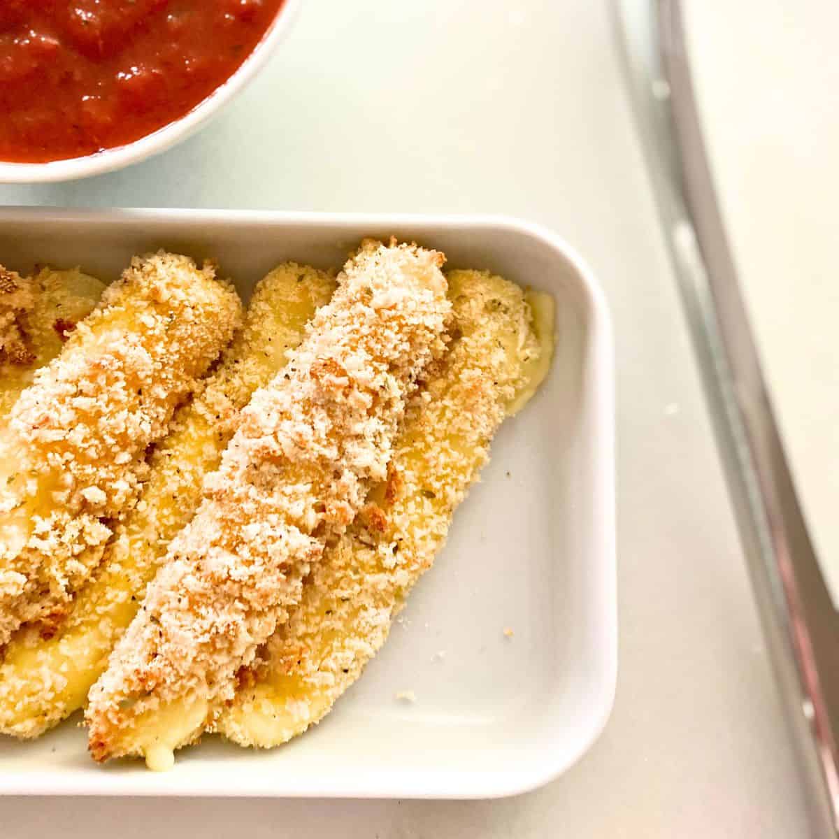 baked homemade cheese sticks with sauce