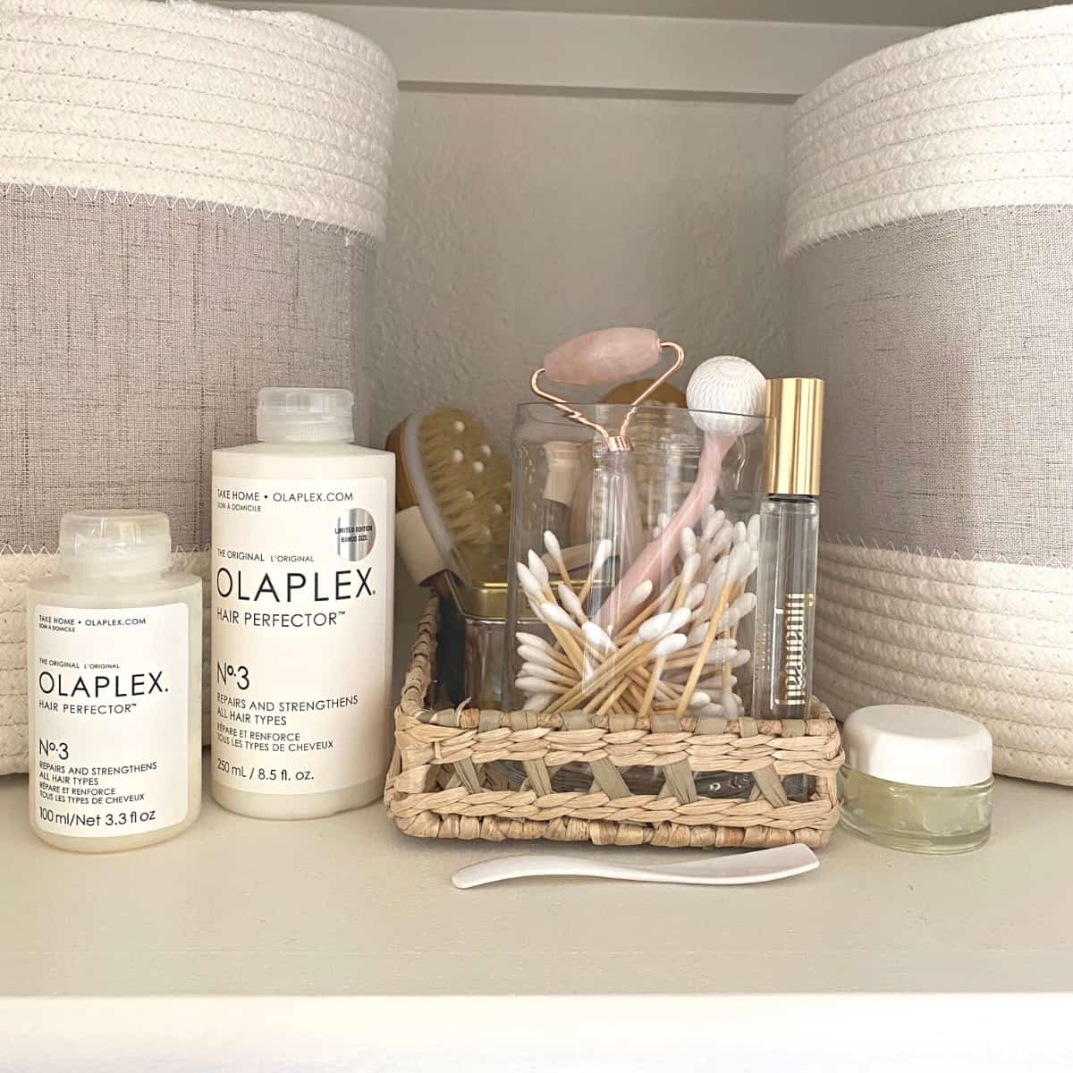 Hair care and body care items on a woven tray, flanked by cotton rope baskets