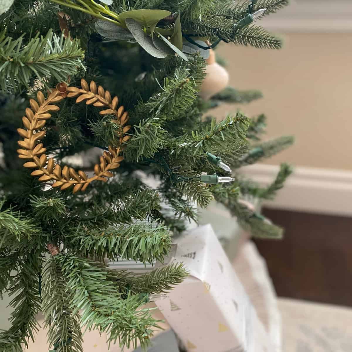 Brass laurel wreath Christmas ornament hangs above neutral presents
