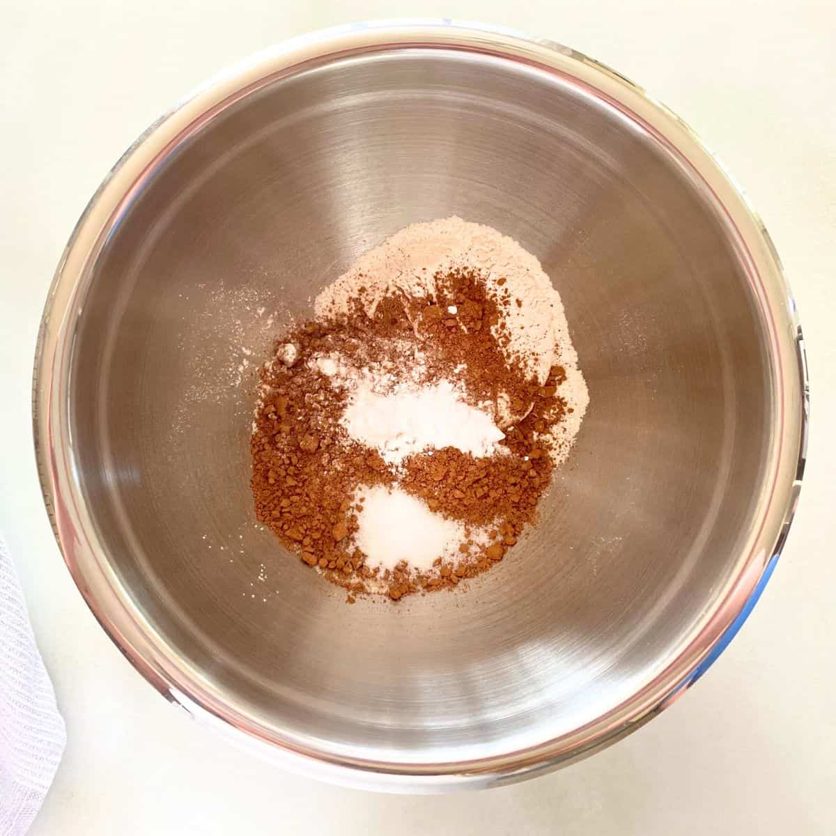 Dry brownie ingredients in a stainless steel mixing bowl