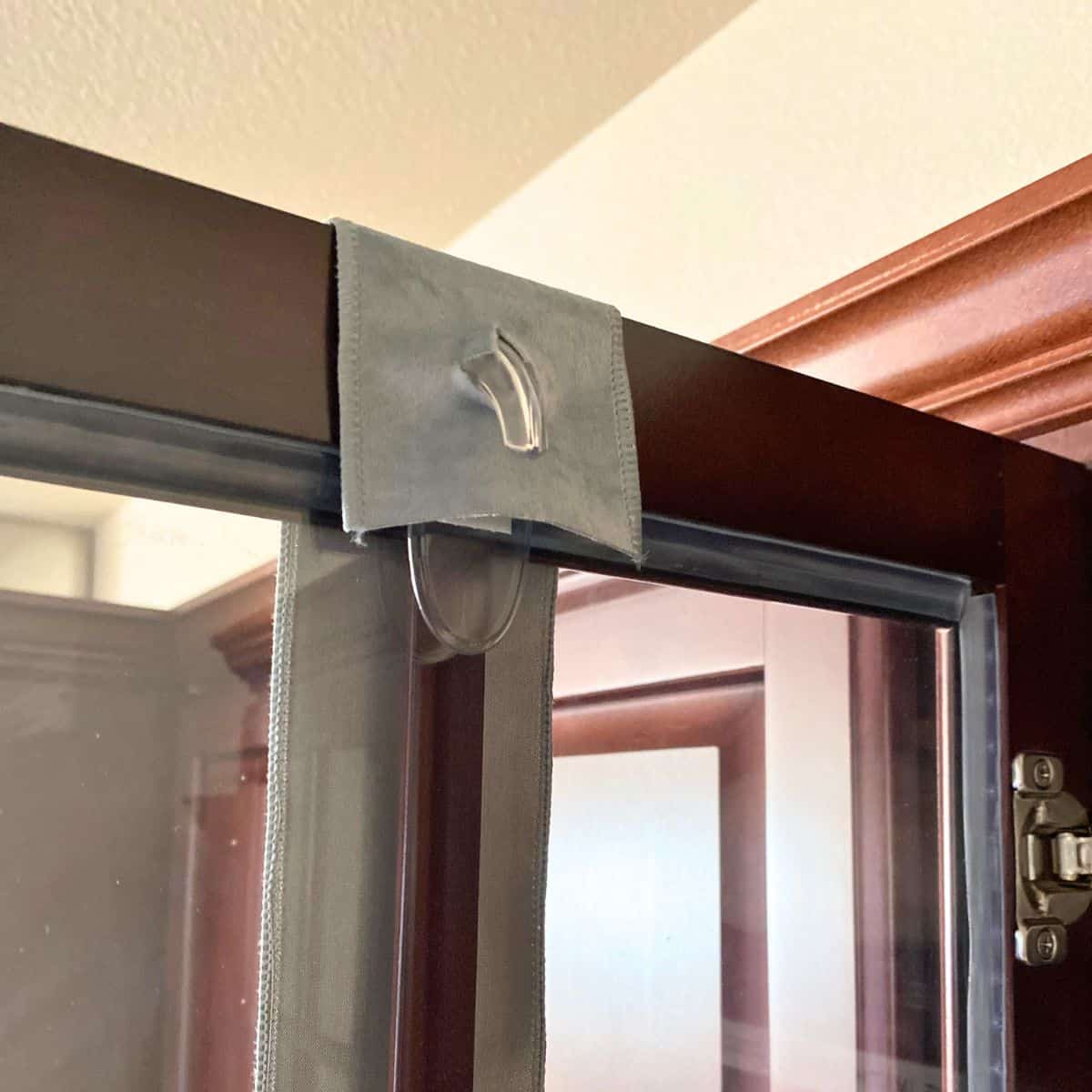 command hook with ribbon through it on inside of cabinet door