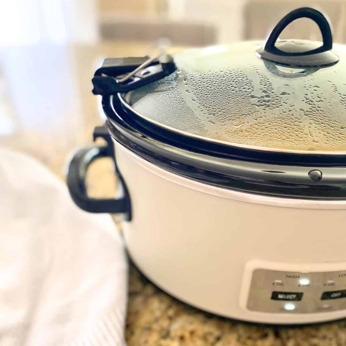 white slow cooker with beaded condensation on the lid