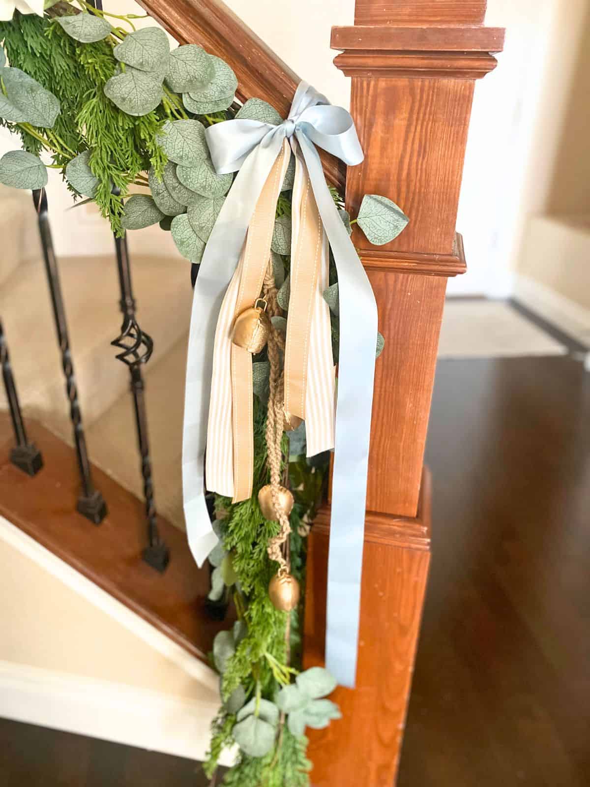 staircase garland with layers of ribbons and bells at the newel post