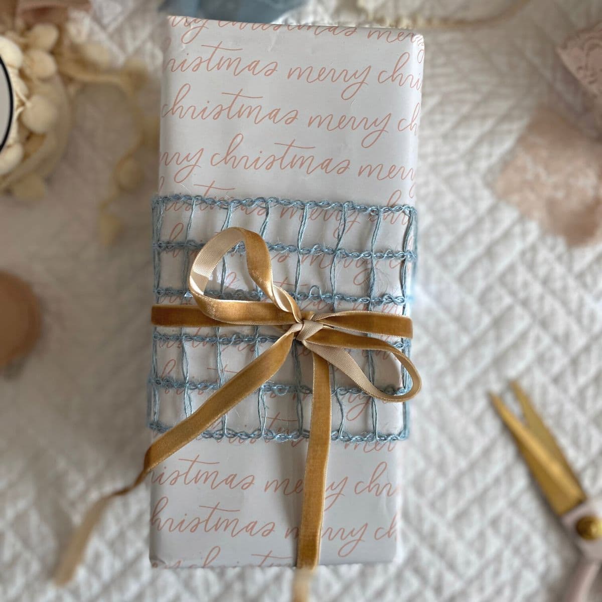 Gift wrapped in Merry Christmas paper, topped with caramel colored velvet bow