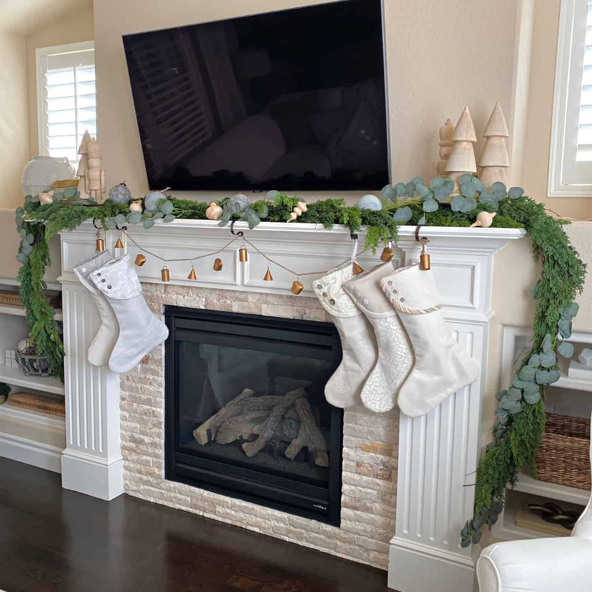 Fireplace mantel decorated for Christmas with greenery garland, stockings and ornaments