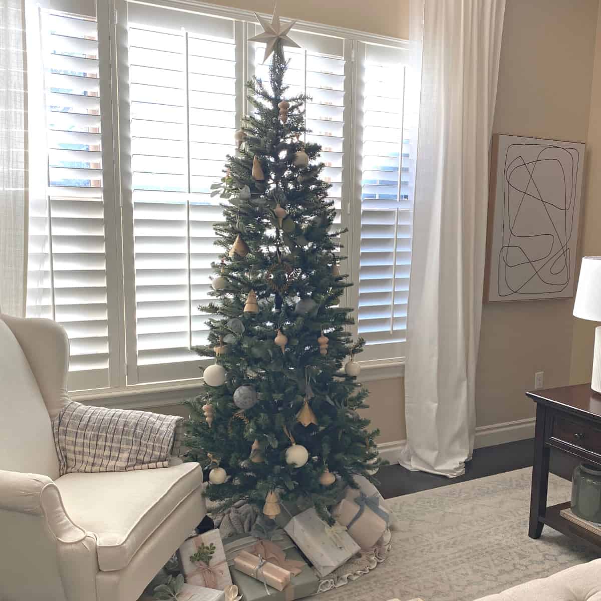 Neutral decorated Christmas tree in a living room with presents beneath