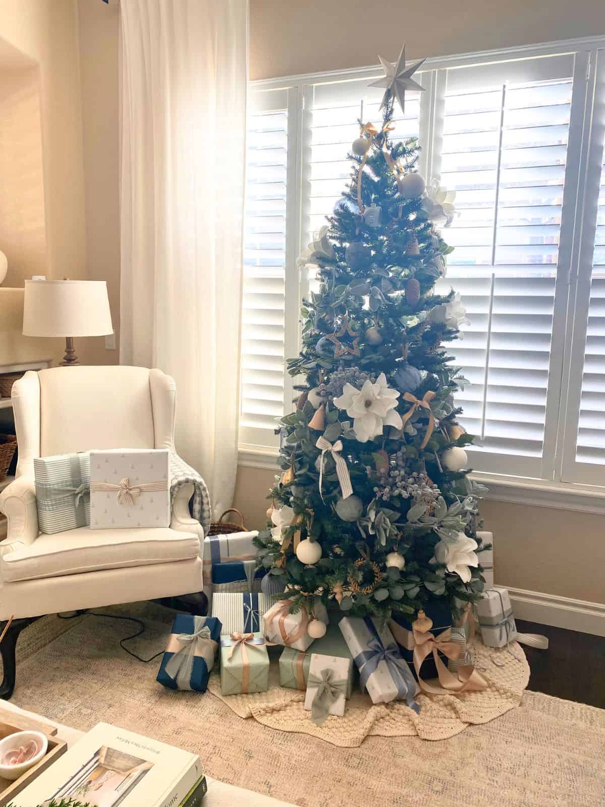 christmas tree with blue, white and green gift wrapped presents under it