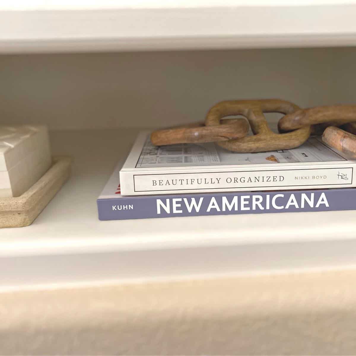 Stack of two neutral coffee table books shelf styled with a wood chain stop.