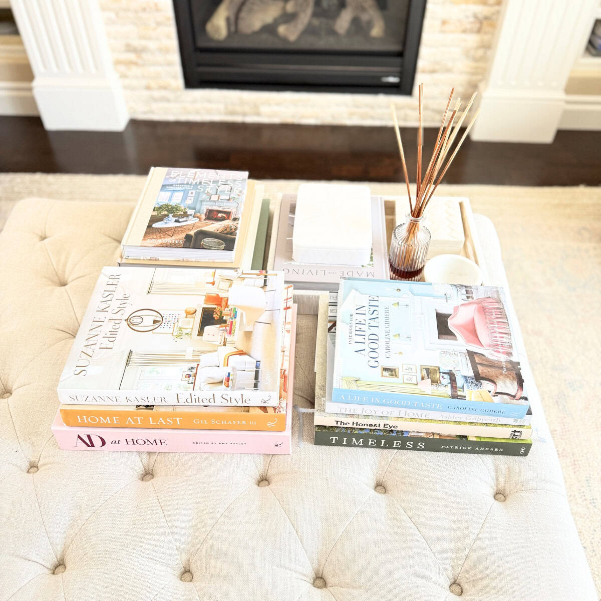 linen tufted ottoman styled with stacked coffee table books