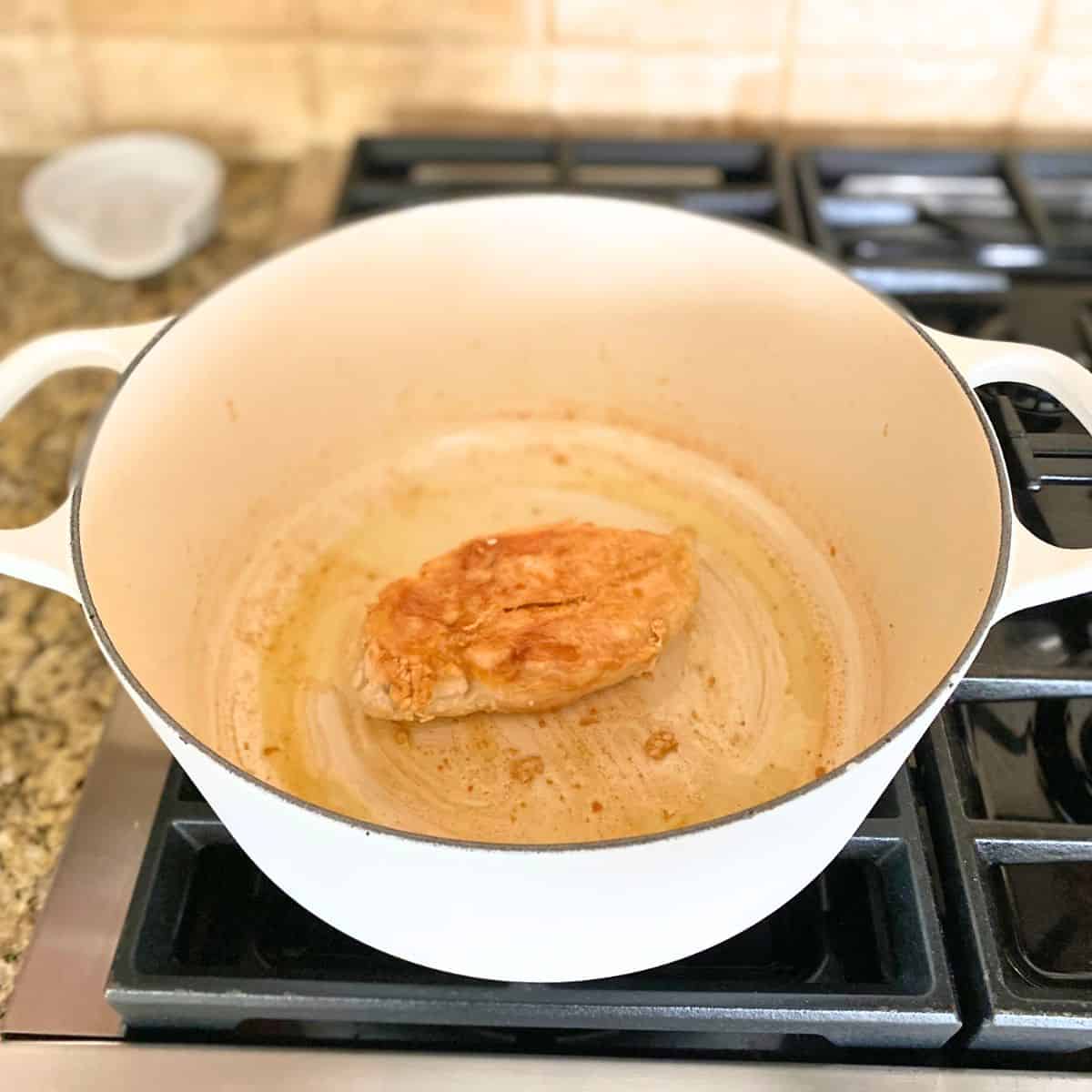 cooked chicken breast in white cast iron pot