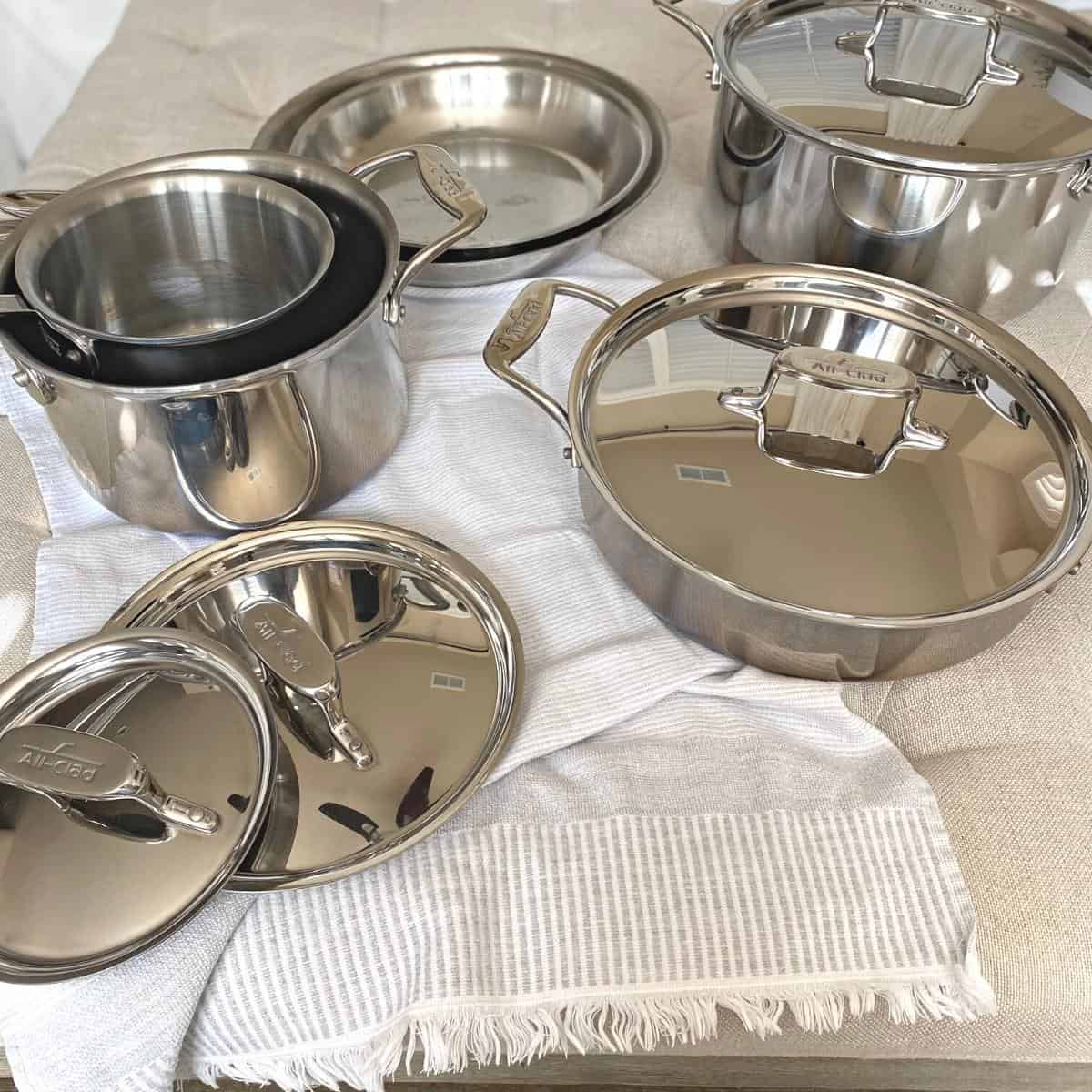 Stainless steel cookware set on a neutral cotton towel