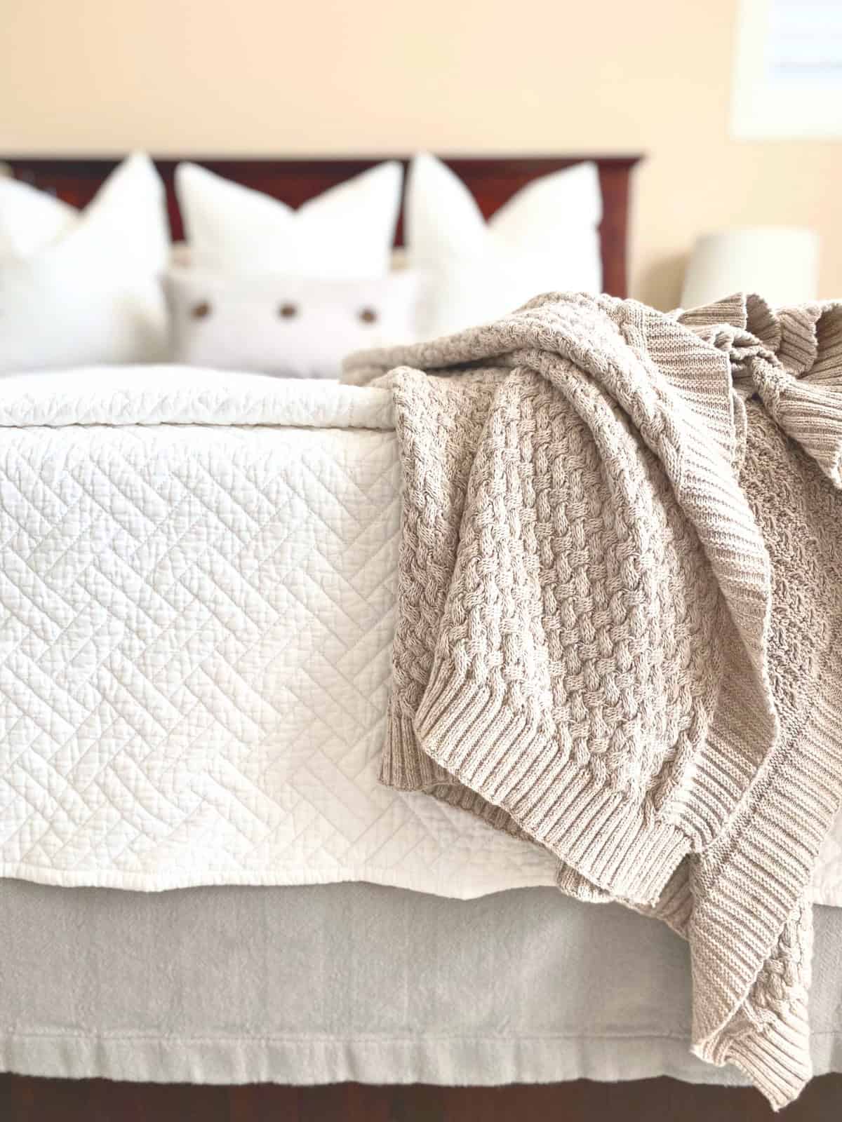 cable knit throw blanket draped over end of bed