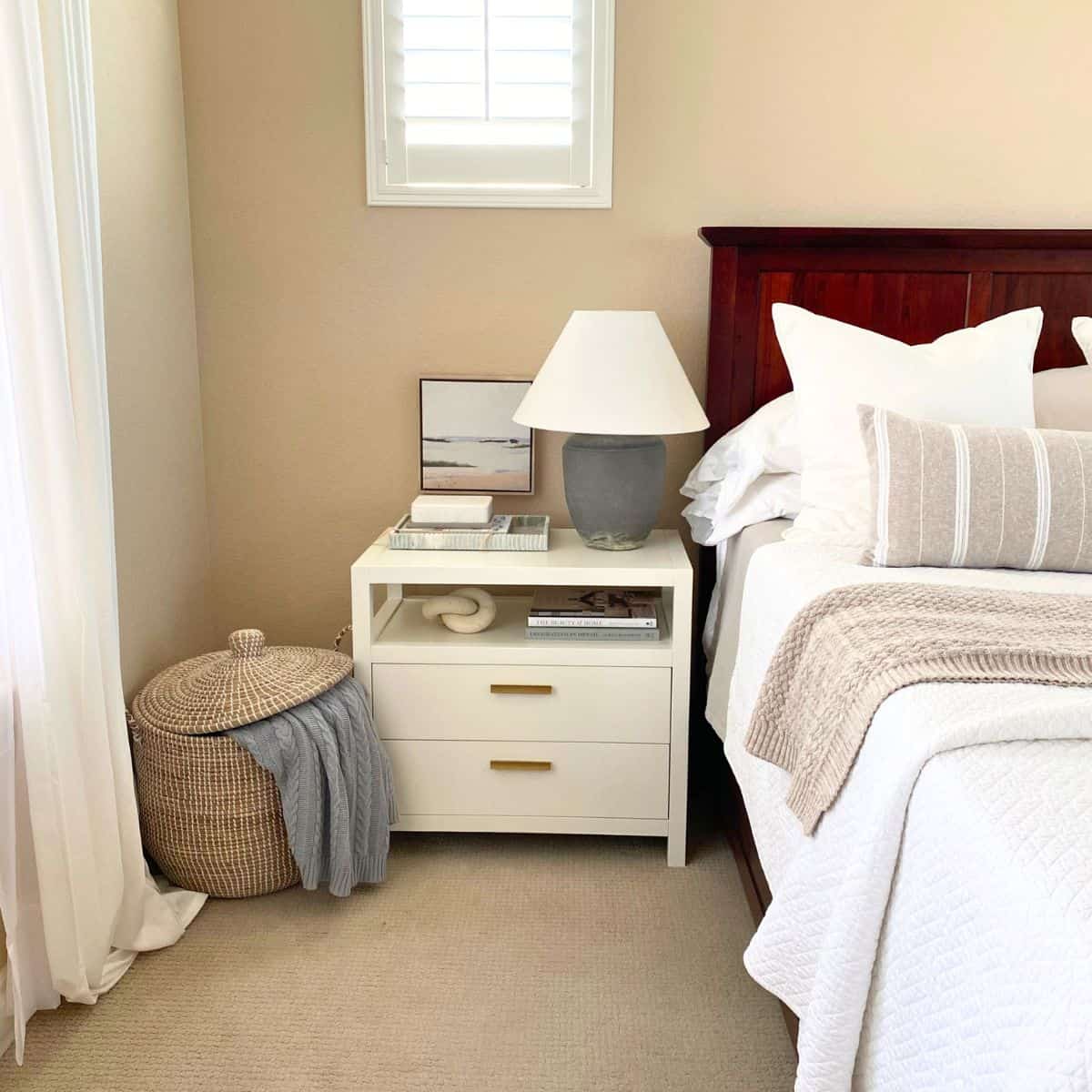 white bedside table next to a tall basket