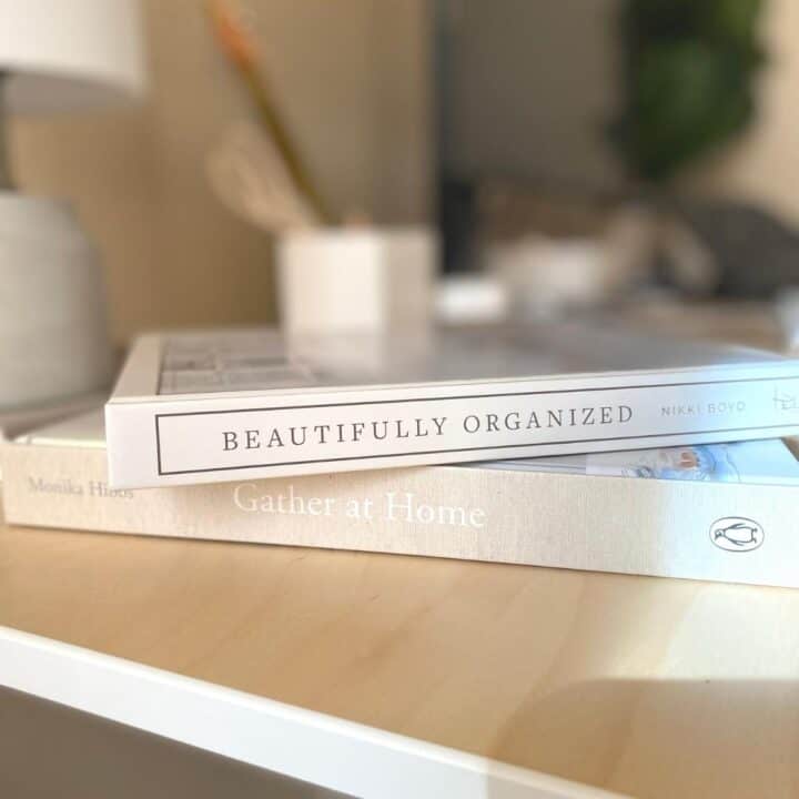 Interior design books stacked on a wood desk to be used as coffee table books. Beautiful Organized book by Nikki Boyd and Gather at Home book by Monika Hibbs.