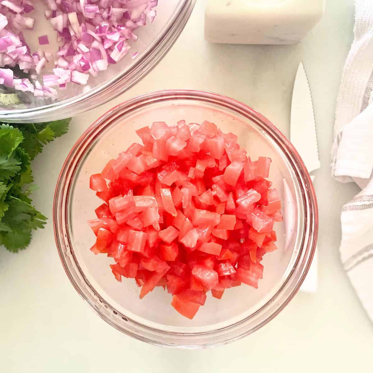 finely diced roma tomatoes in a glass mixing bowl