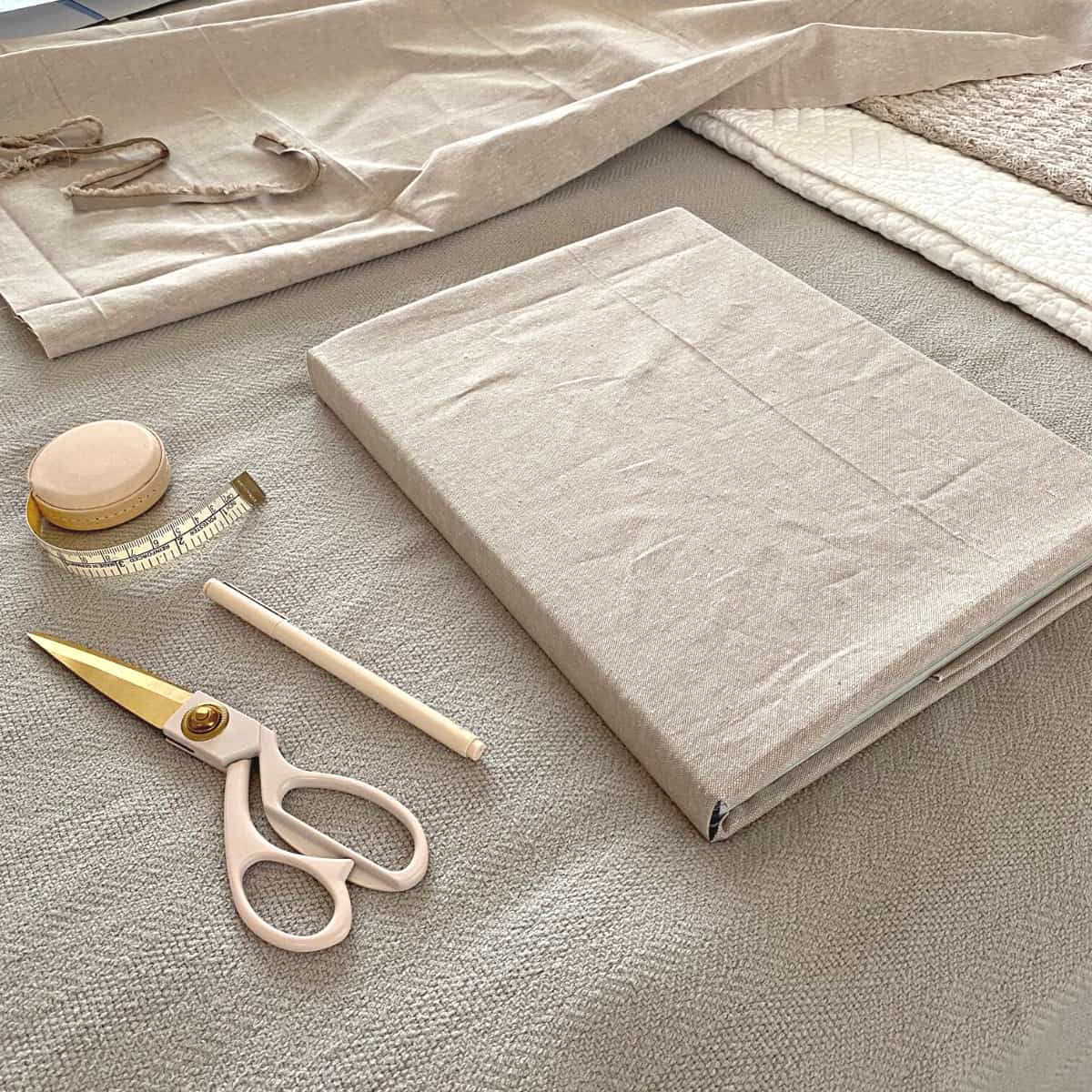 Linen fabric covered book with tape measure, scissors and pen