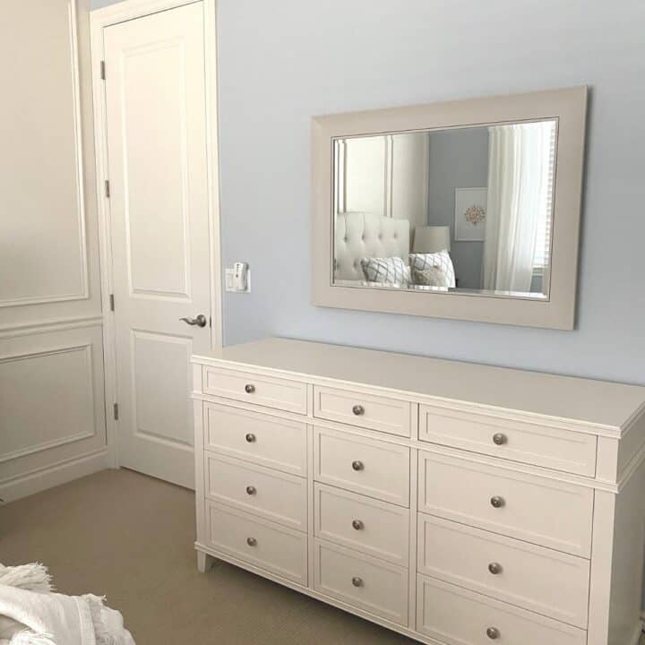 The completed mirror shown from farther away in the guest bedroom. It is hung over a long white twelve drawer dresser.