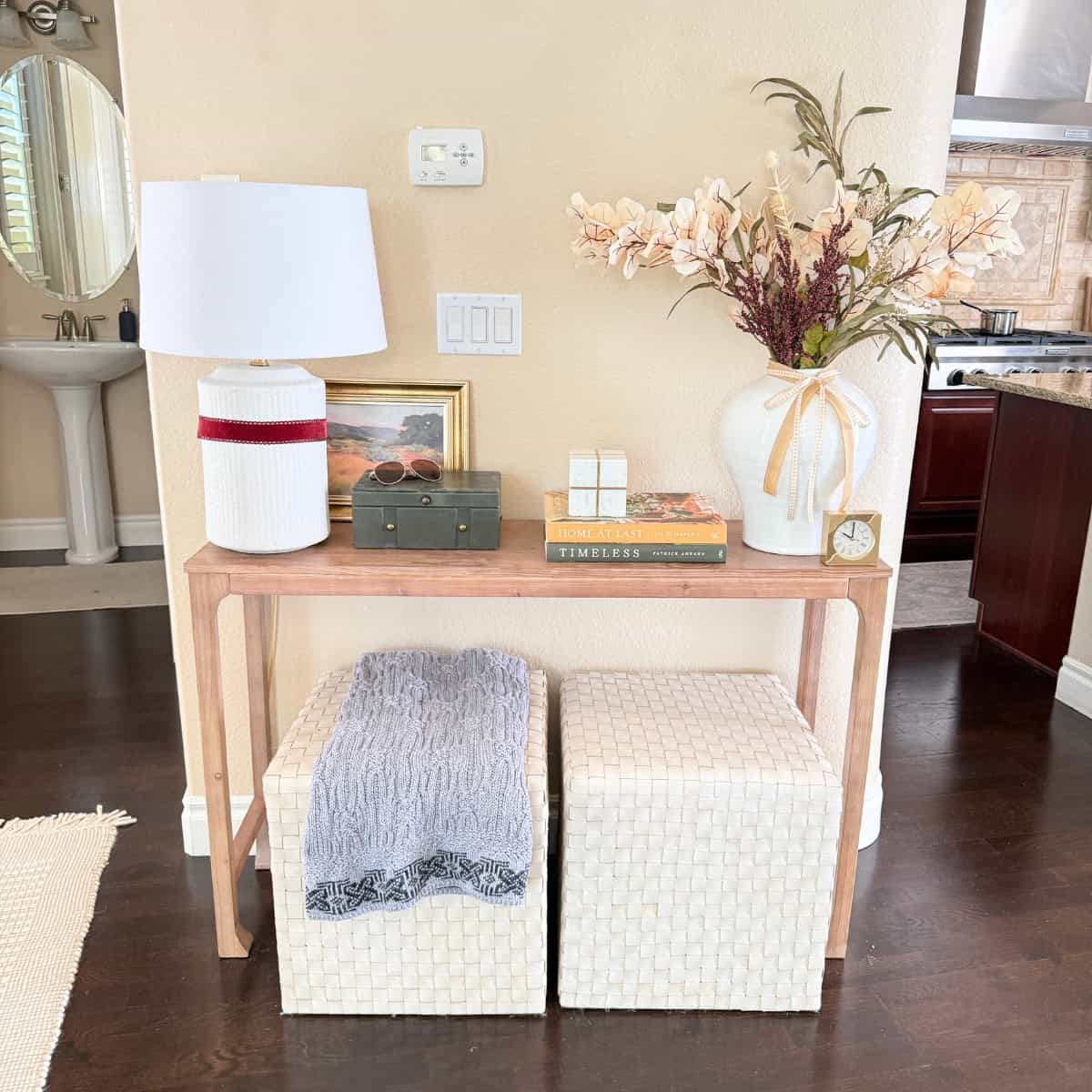 console table styled for fall with a dark green velvet box and a white vase with various fall colored stems