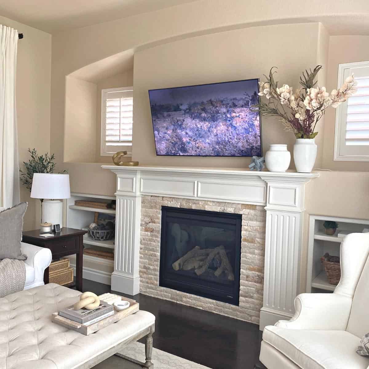 Living room decorated for fall, with a fireplace and fall floral stems