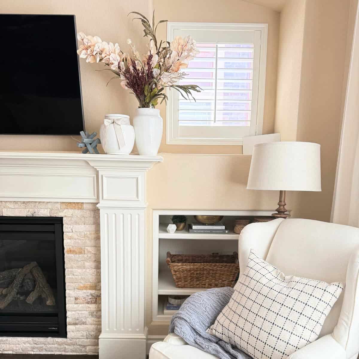 fireplace mantel styled with a white vase with faux stems in fall colors