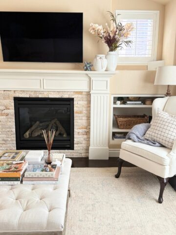 fireplace mantel styled with a white vase with faux stems in fall colors