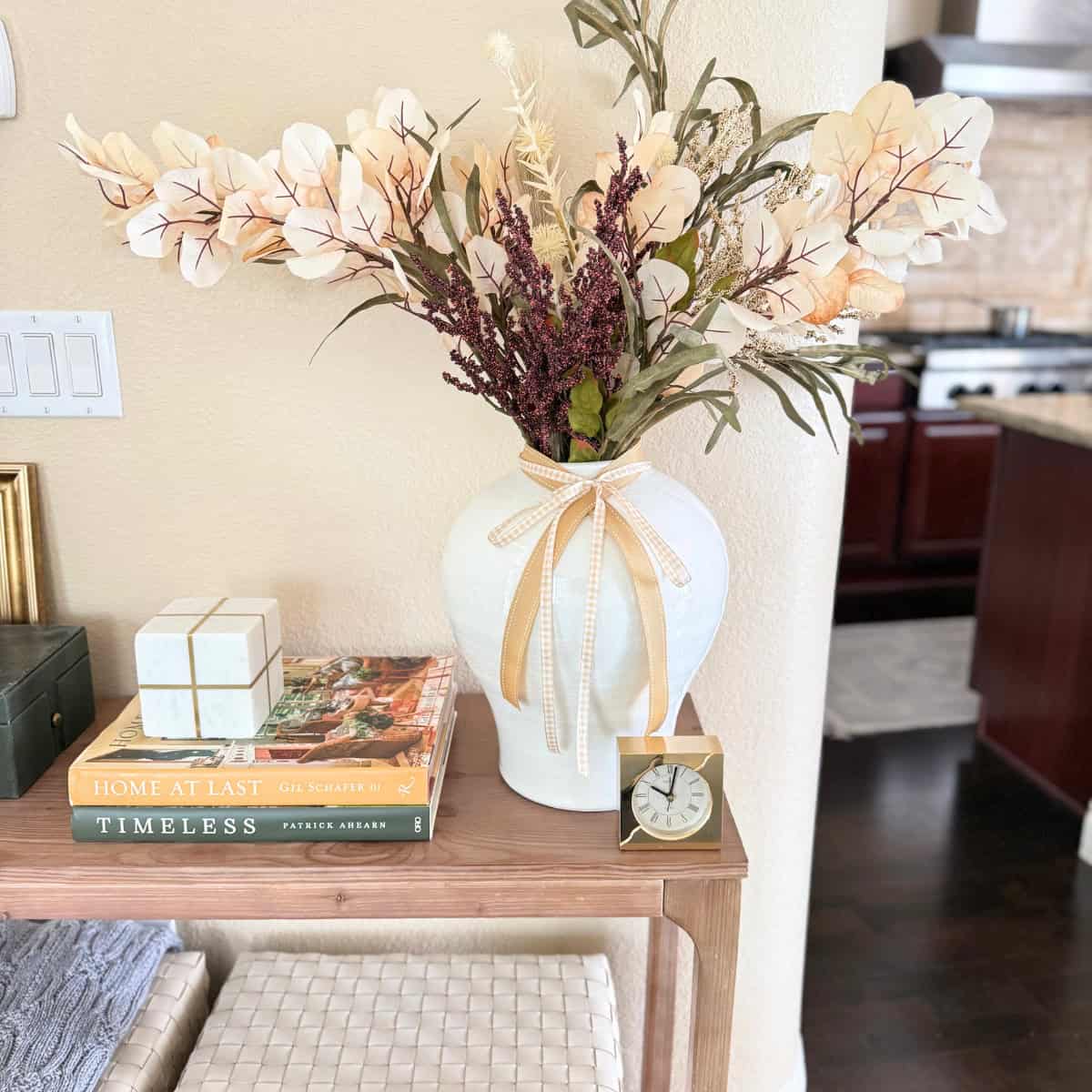 tall white vase with faux stems in fall colors