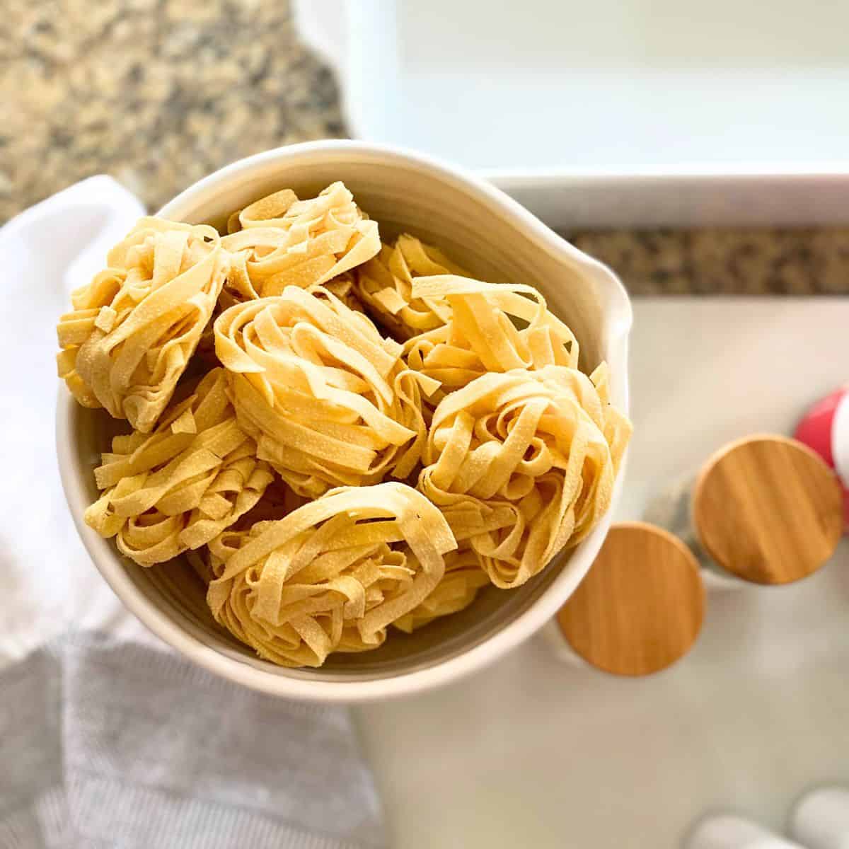 Fettuccine pasta nests in ceramic mixing bowl