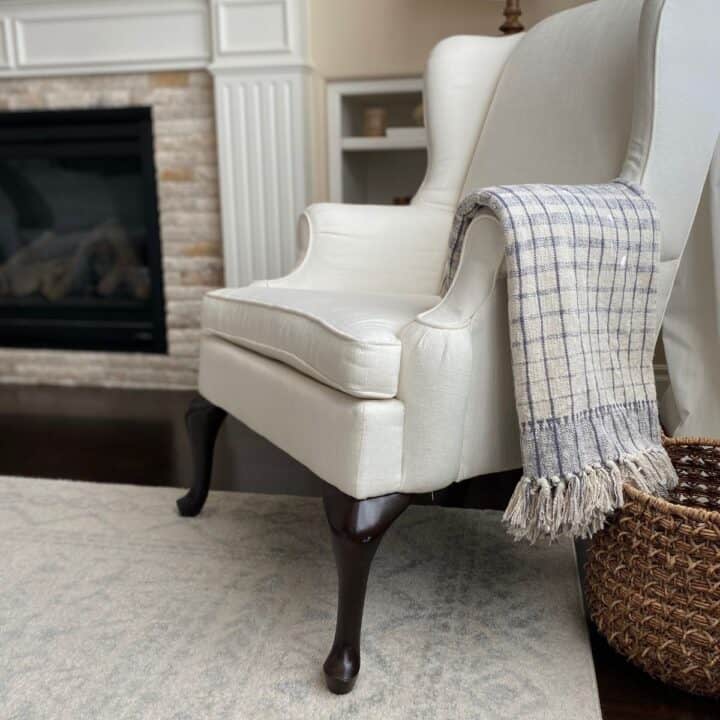 Decorative image of wing back chair with a striped throw blanket draped over the side to show you can use rubbing alcohol to repel dust on certain materials for furniture and decor