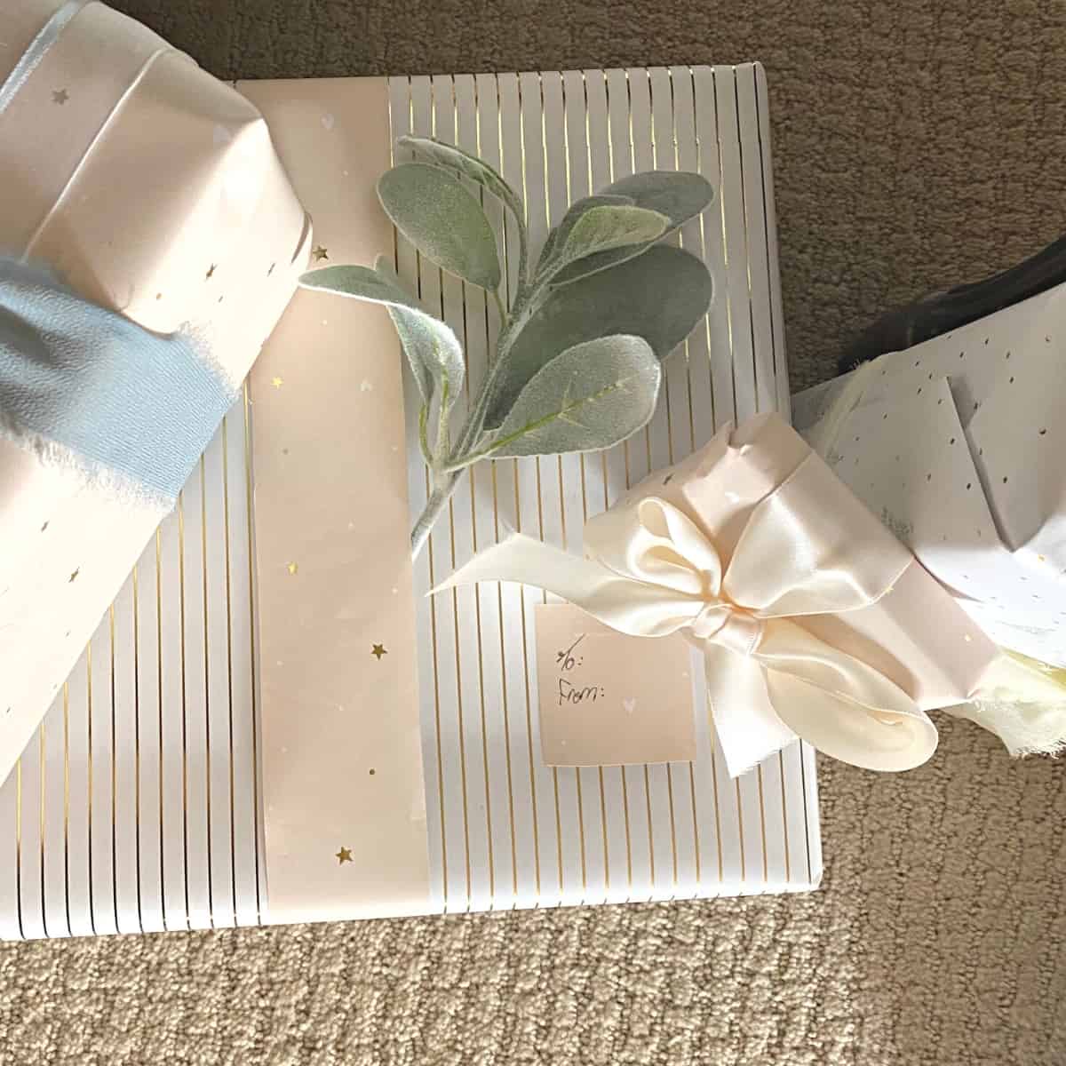 Gold stripe present, a sprig of lambs ear greenery, flanked by other neutral wrapped gifts