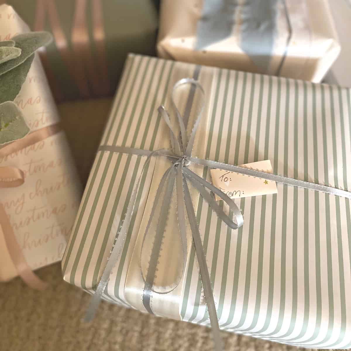 A present wrapped in a gray-green striped paper with a blue satin ribbon bow