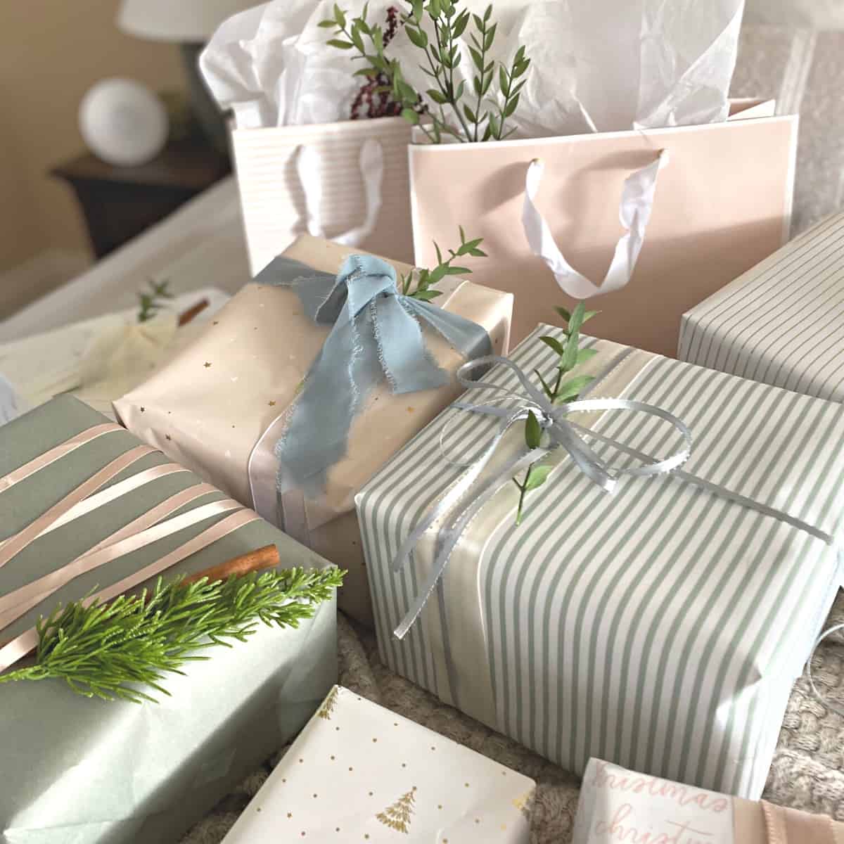 Assorted neutral pastel wrapped gifts with ribbon and sprigs of greenery