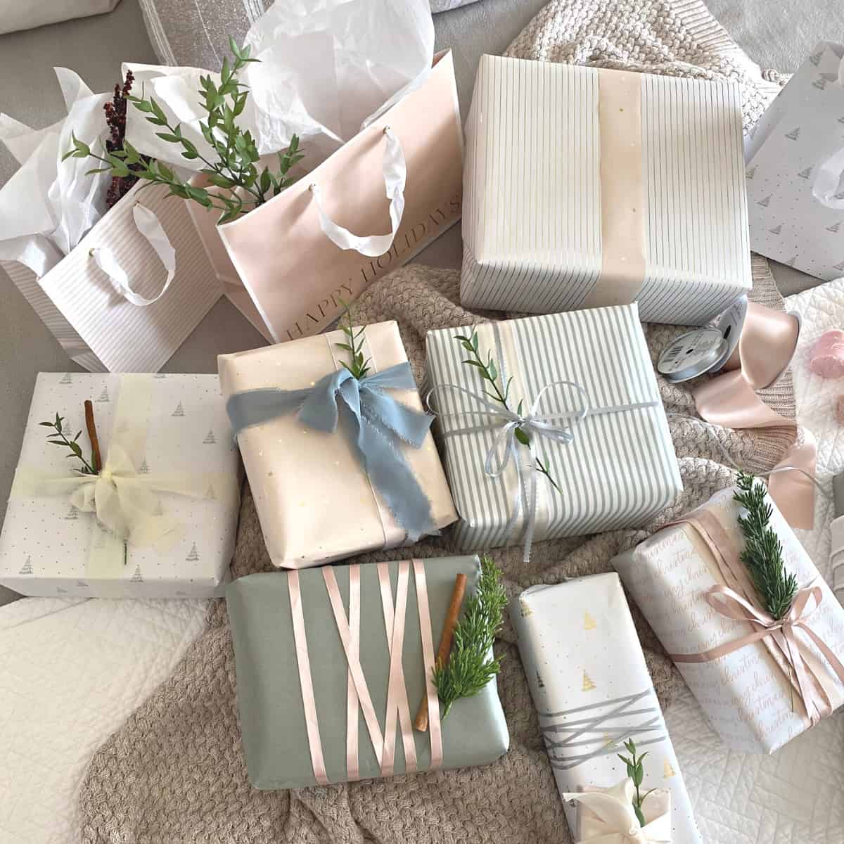 Assorted neutral pastel wrapped gifts with ribbon and sprigs of greenery