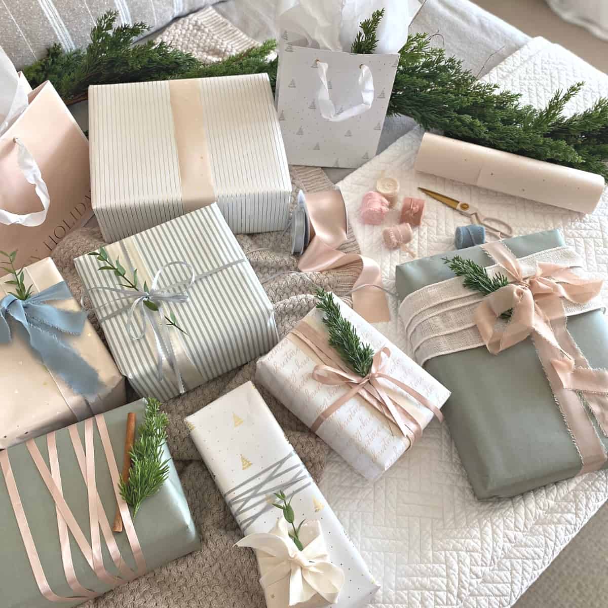 Assorted neutral pastel wrapped gifts with ribbon and sprigs of greenery