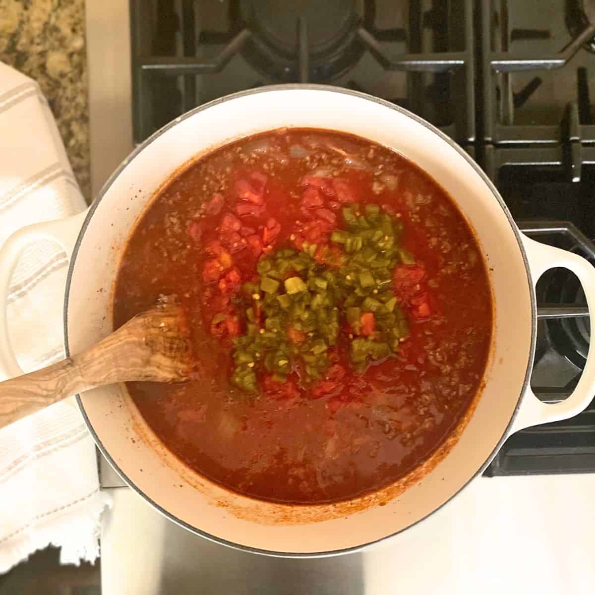Added green chiles and diced tomatoes to chili on stove