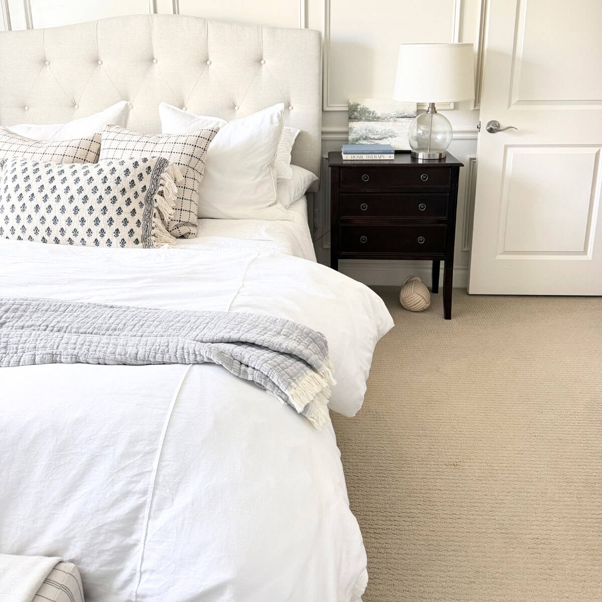upholstered bed next to dark wood nightstand