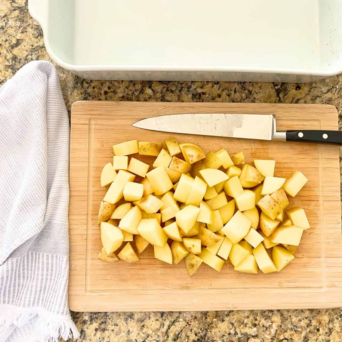 Four cubed raw yellow potatoes atop a cutting board