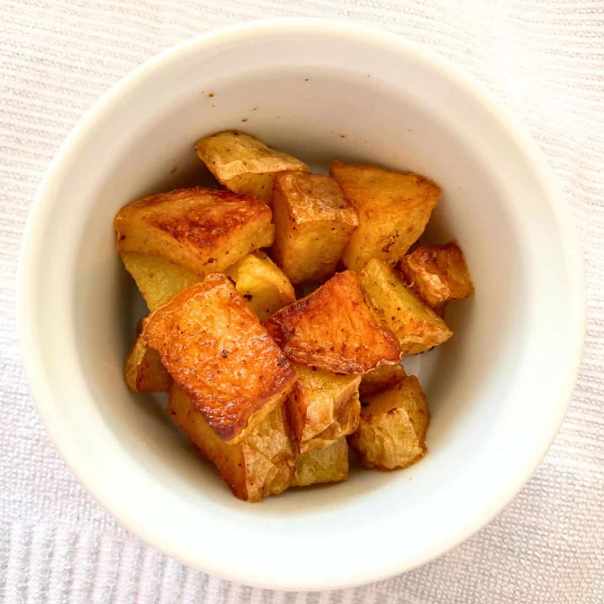 Home fries in a white Apilco ramekin atop a Turkish towel