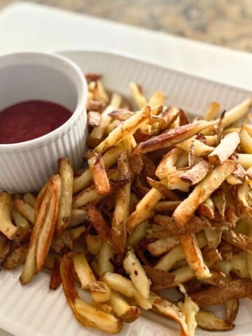 Baked French fries on a platter with ketchup