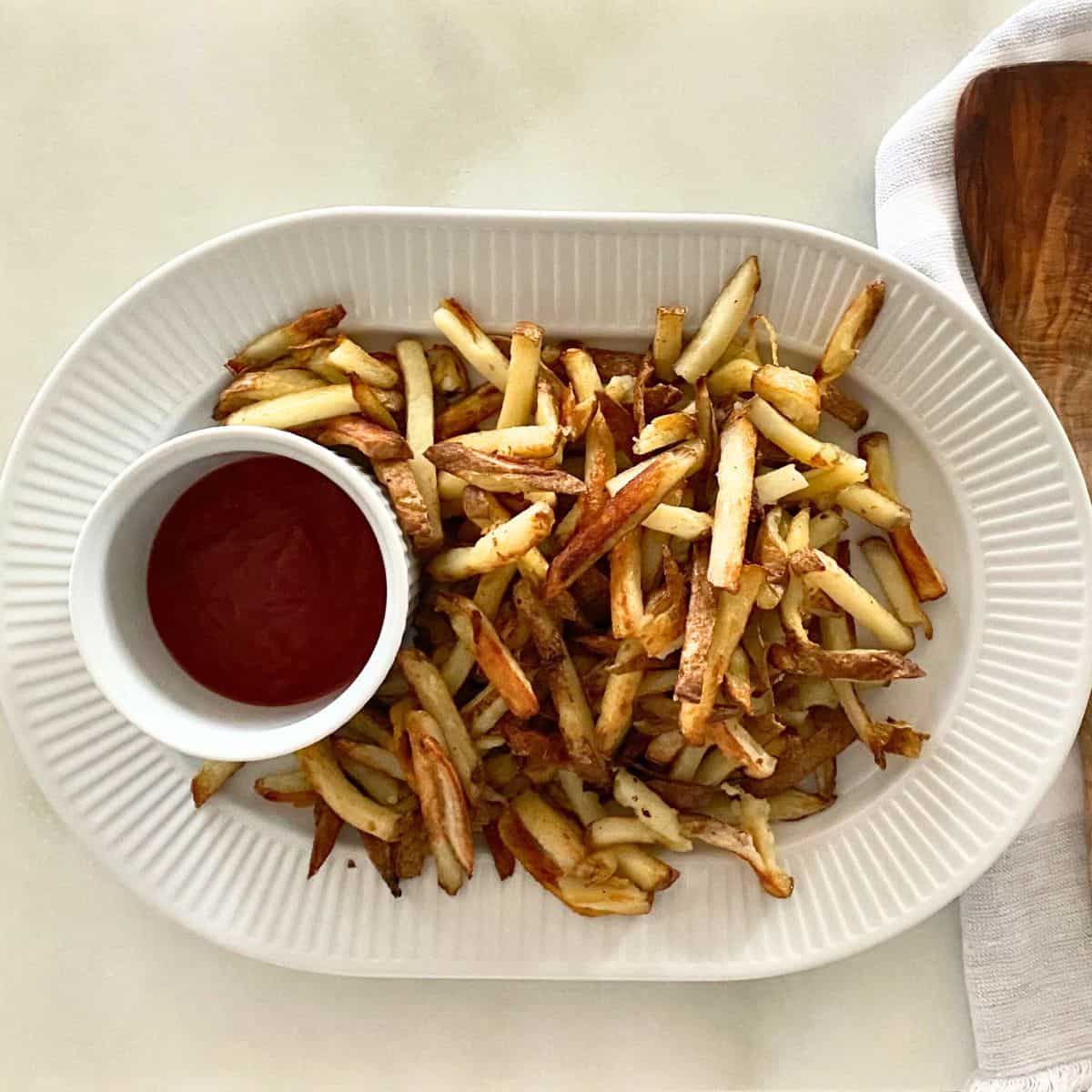 Homemade French fries on a platter with ketchup
