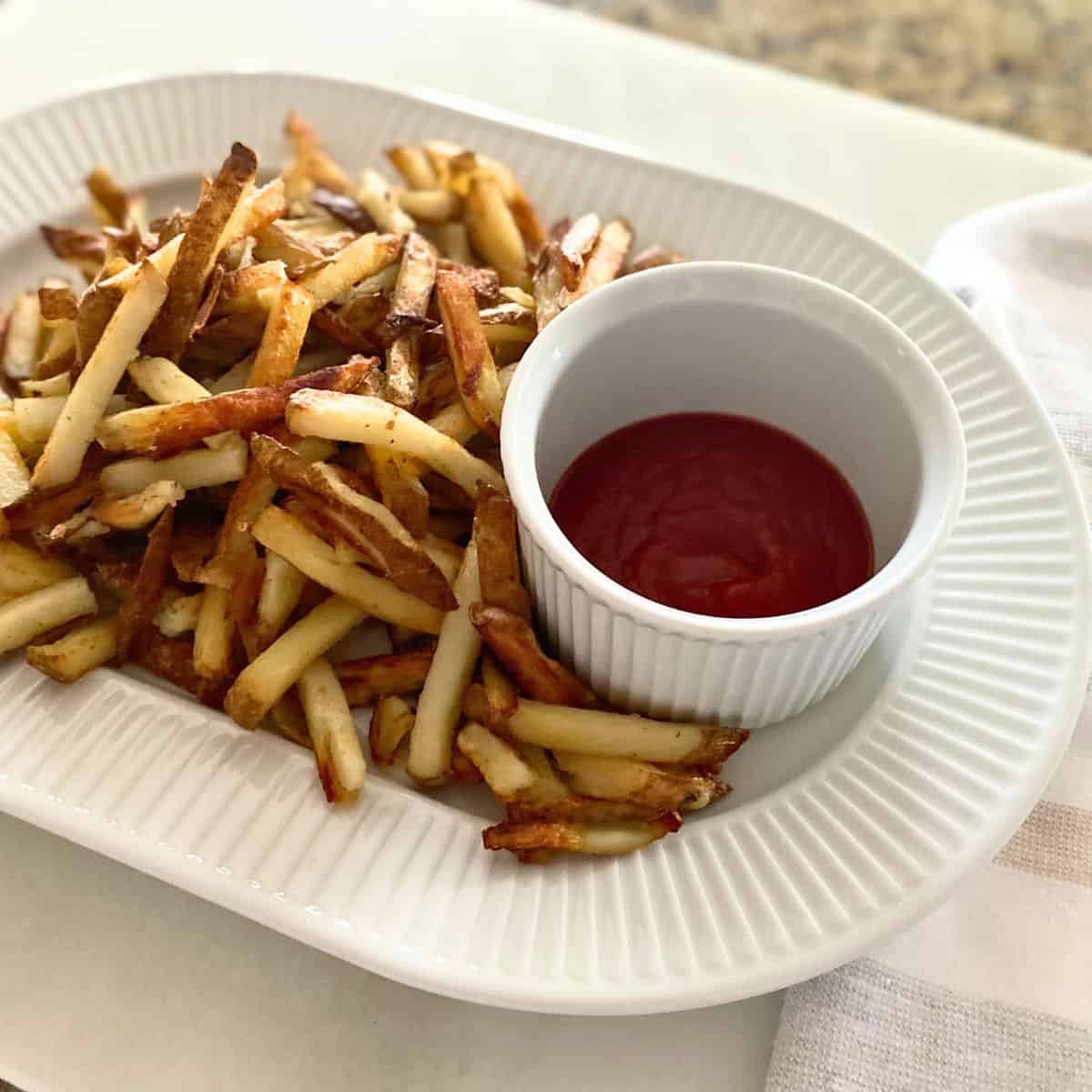 Homemade French fries on a platter with ketchup
