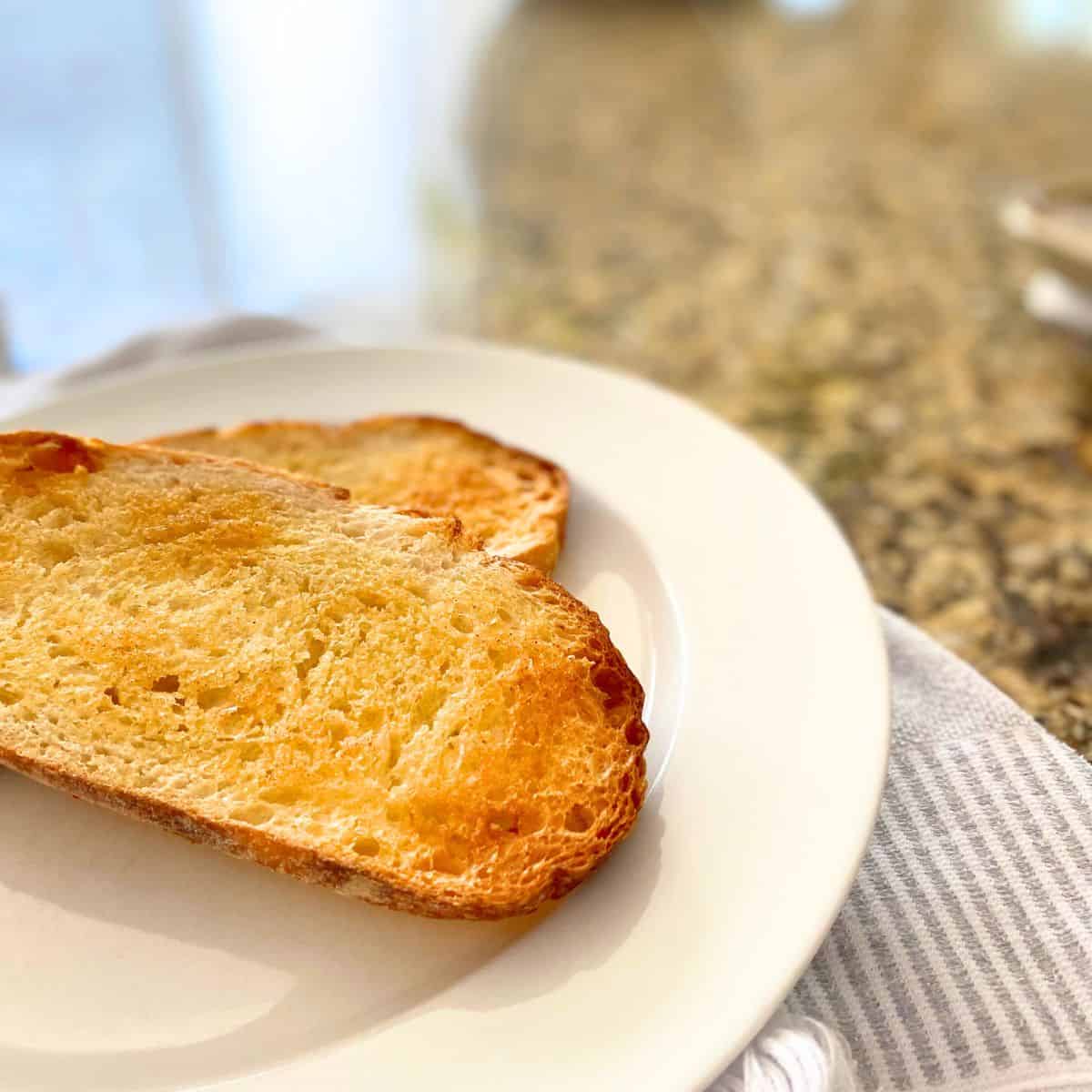 Homemade garlic bread roasted in the oven on a white dinner plate