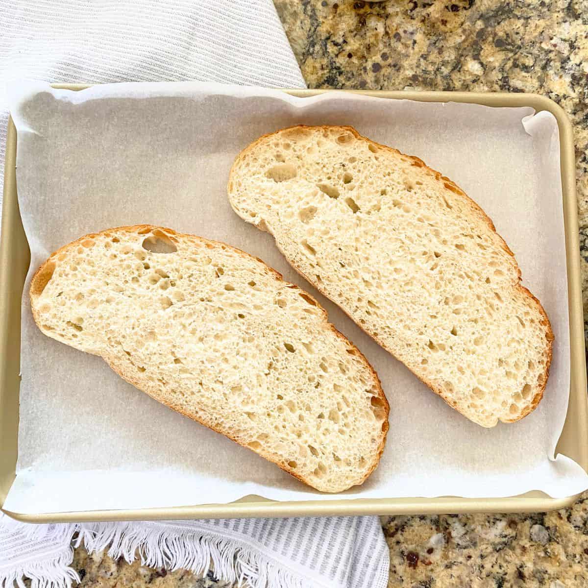 Sourdough bread on a gold baking sheet pan, waiting to be roasted in the oven