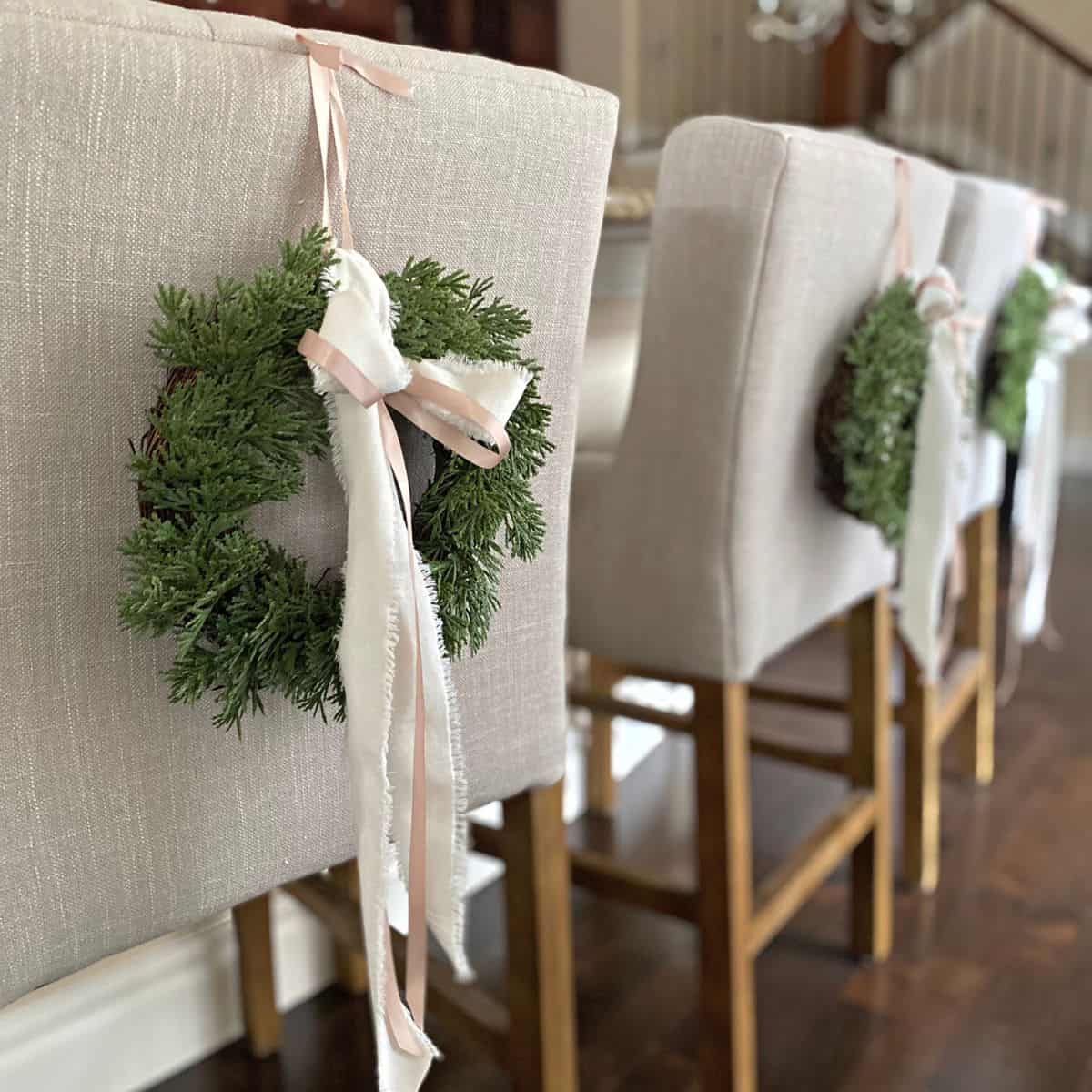 three pretty holiday wreaths on the backs of chairs