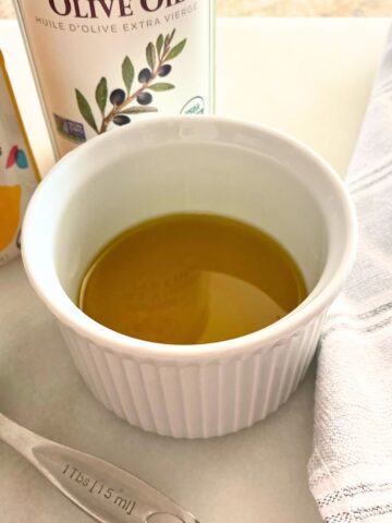 A mixture of lemon and olive oil in a white ramekin for salad dressing