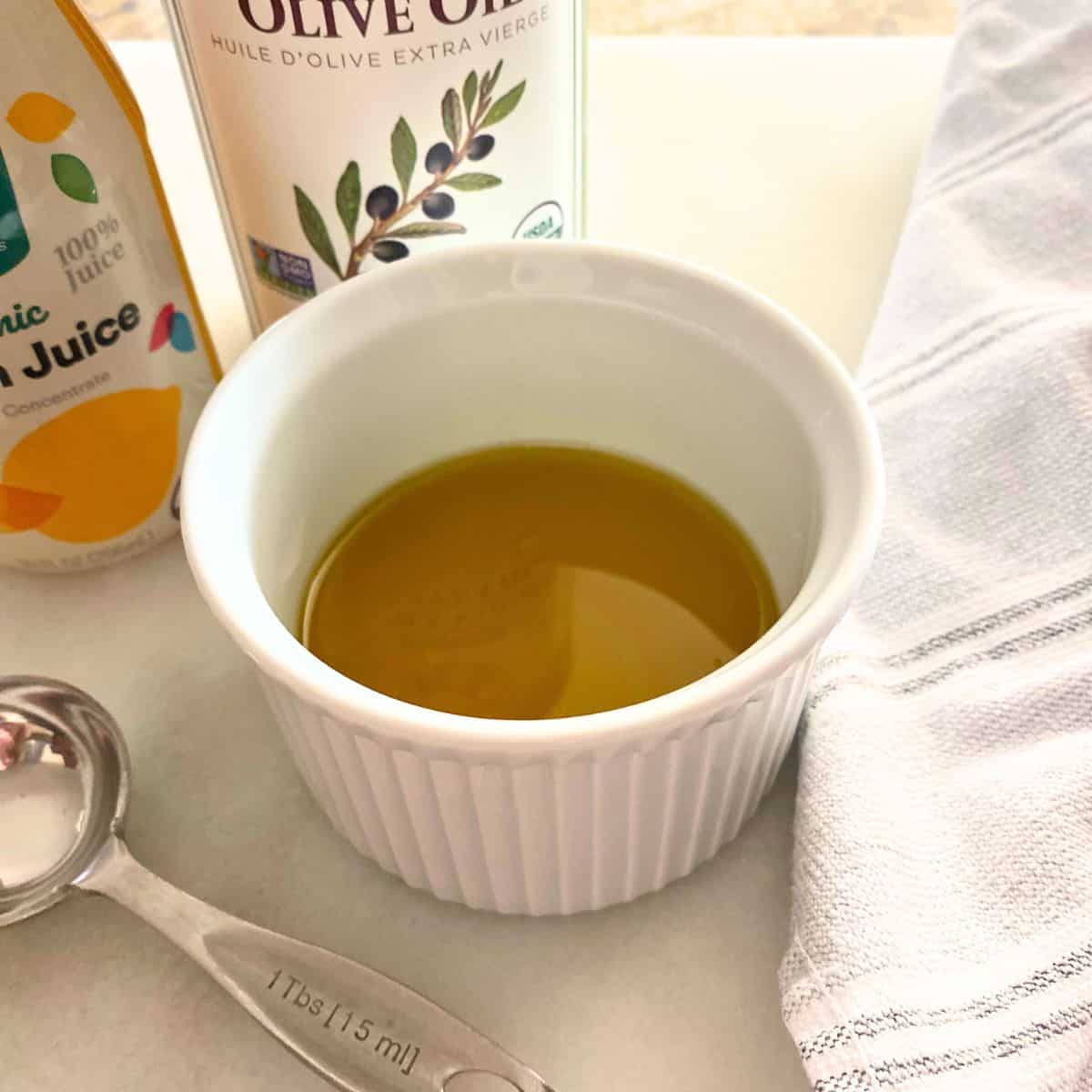 A mixture of lemon and olive oil in a white ramekin for salad dressing
