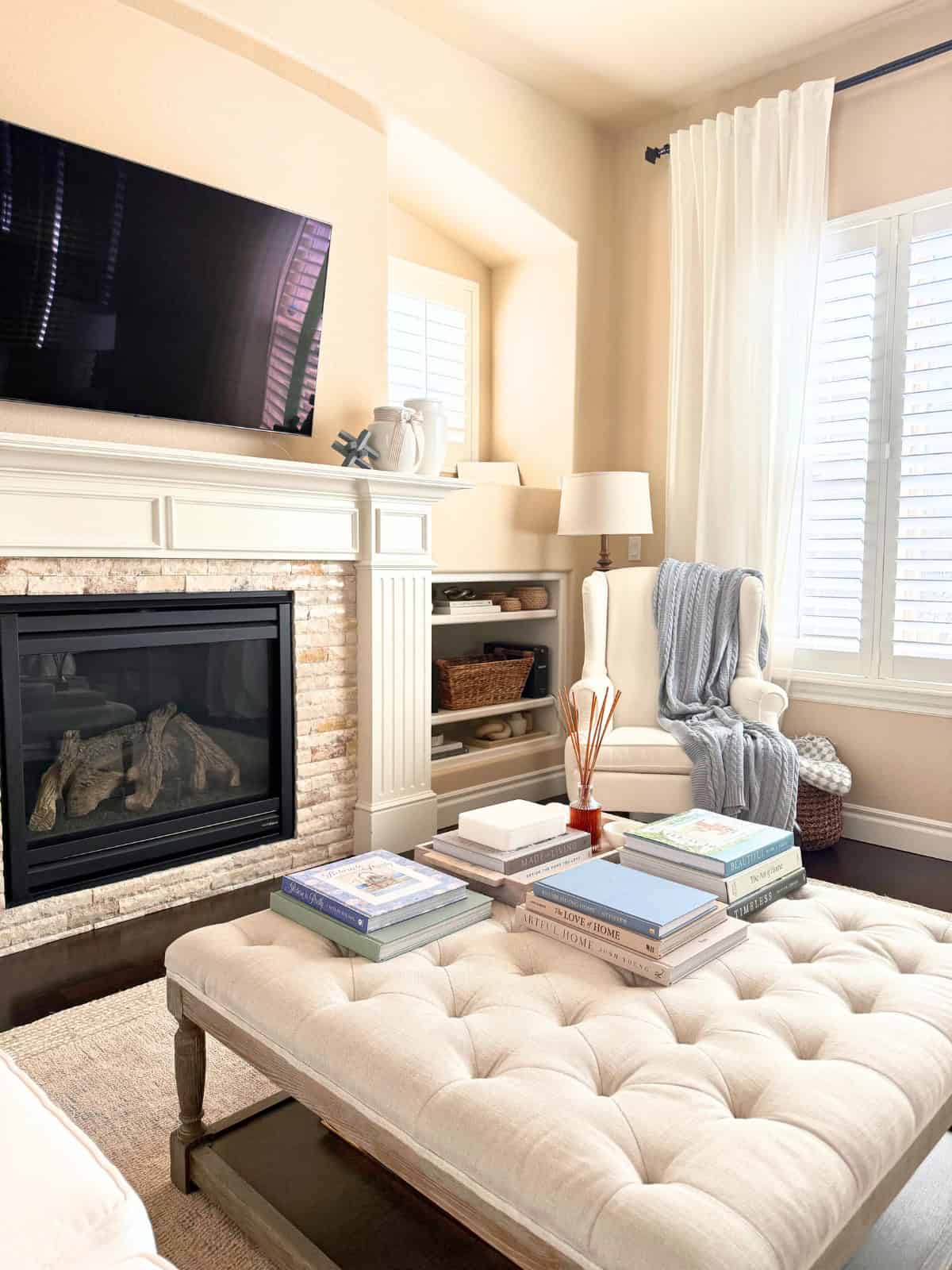 tufted ottoman styled with books in a living room