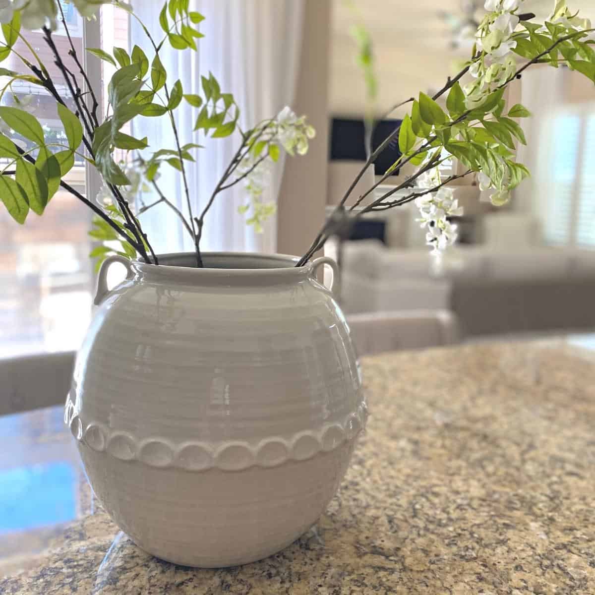Large white stoneware vase atop granite kitchen countertop