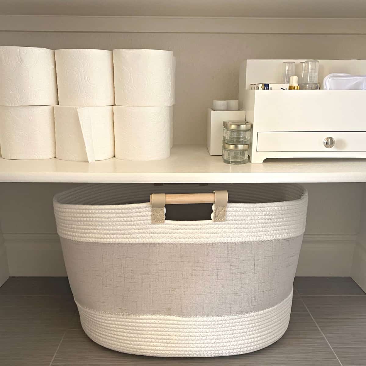 Organized stacks of rolls of tissue paper and hair tools organizer on a shelf above a cotton basket