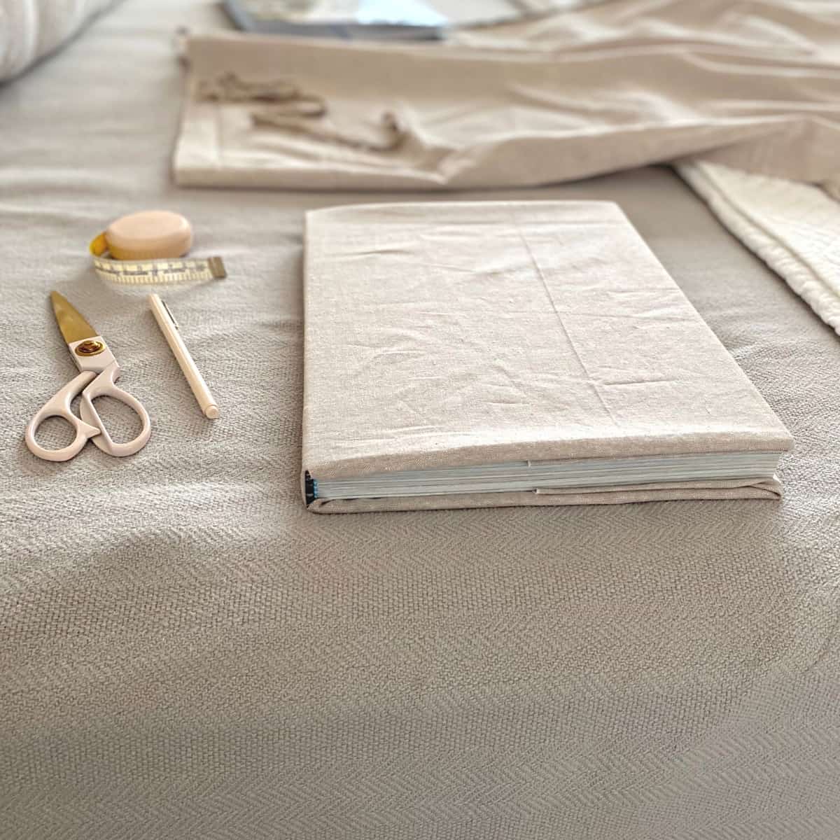 Linen fabric covered book with tape measure, scissors and pen